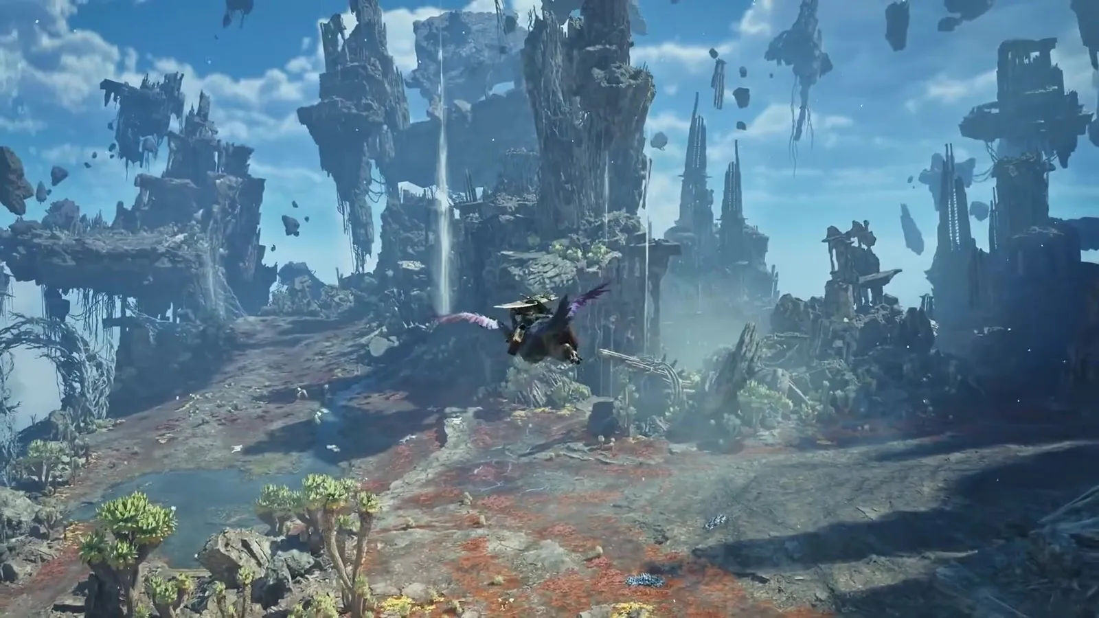 A hunter gliding over red grass below floating rock spires and a waterfall in the Skybound Eyrie, Monster Hunter Wilds Ascendance